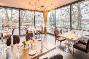 ein Restaurant mit Tischen und Stühlen und großen Fenstern in der Unterkunft Haus am Spreebogen in Fürstenwalde
