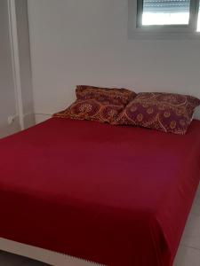 a red bed with two pillows on top of it at VILLA BÖ LANME in Le Carbet