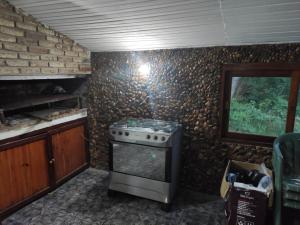 a kitchen with a stove and a stone wall at Casa playa hermosa 3 dormitorios in Playa Hermosa