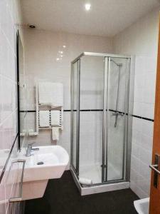 a white bathroom with a shower and a sink at Apartamentos Internacional in Coimbra