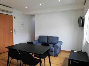 Una sala de estar con un sofá azul y una mesa. en Apartamentos Internacional, en Coímbra