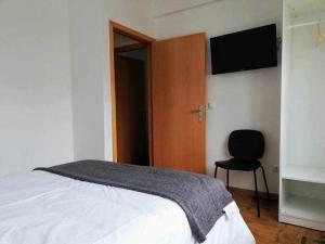 Un dormitorio con una cama y una silla y un televisor. en Apartamentos Internacional, en Coímbra