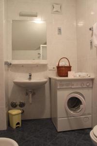 ein Badezimmer mit einer Waschmaschine und einem Waschbecken in der Unterkunft Villa Grünewald in Seis am Schlern