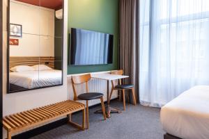 um quarto de hotel com uma mesa e duas cadeiras e uma televisão em Weber Hotel 117 em Amsterdã