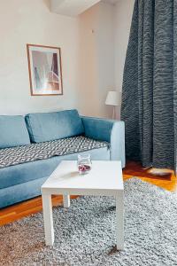ein Wohnzimmer mit einem blauen Sofa und einem weißen Tisch in der Unterkunft He-Ra apartment 6 with Free Netflix in Skopje