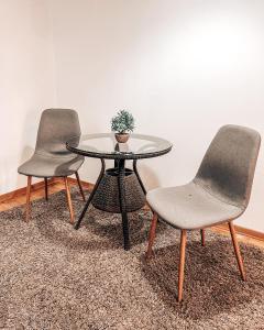 zwei Stühle und ein Glastisch mit einer Pflanze drauf. in der Unterkunft He-Ra apartment 6 with Free Netflix in Skopje