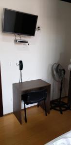 einen Schreibtisch mit einem Ventilator und einem TV an der Wand in der Unterkunft Hotel Flórida in União da Vitória