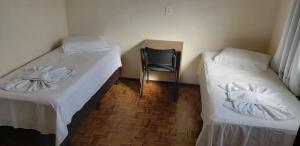 ein Zimmer mit 2 Betten und einem Stuhl darin in der Unterkunft Hotel Flórida in União da Vitória