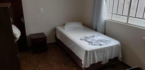 Cama pequeña en habitación pequeña con ventana en Hotel Flórida, en União da Vitória