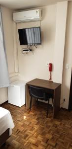 a room with a desk and a television on a wall at Hotel Flórida in União da Vitória