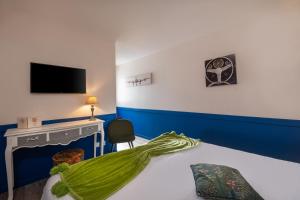 a bedroom with a bed with a tv and a desk at LE M HOTEL & SPA HONFLEUR in Honfleur