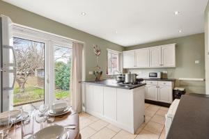a kitchen with green walls and white cabinets and a table at Beautiful 4 Bed in Kent - Parking - Sleeps 7 in Kent