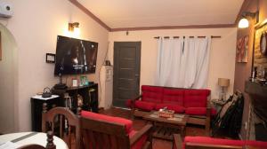 ein Wohnzimmer mit einem roten Sofa und einem TV in der Unterkunft FINCA EL BRACO in Santiago del Estero