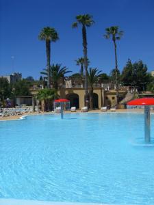 ein großer Pool mit Palmen im Hintergrund in der Unterkunft Sporting Club Village in Mazara del Vallo