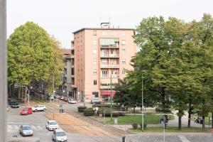 een stadsstraat met auto's die voor een gebouw geparkeerd staan bij Spazio Stoppani - BIG in Milaan