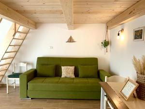 a green couch in a living room with wooden ceilings at Elicriso Home in Porto Torres