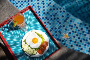 a plate of food with an egg and cucumbers and a drink at Cocohut Hoi An Homestay in Hoi An