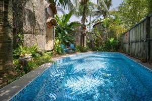 a large blue swimming pool in a yard at Cocohut Hoi An Homestay in Hoi An