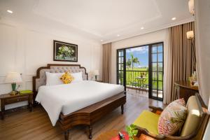 a bedroom with a large white bed and a balcony at Maison Fleur Luxury Hoi An in Hoi An