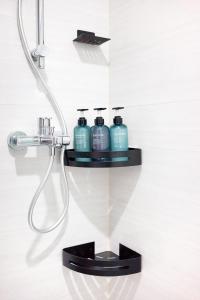 a shower with three blue bottles on a shelf at CoLiving - Lockhart Road 388 in Hong Kong
