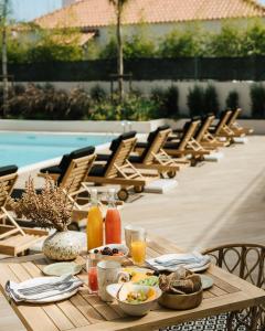 a wooden table with food and drinks on a patio at AlmaLusa Comporta in Comporta