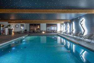 una piscina notturna con sedie intorno di LE M HOTEL & SPA HONFLEUR a Honfleur