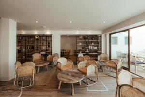 a waiting room with chairs and tables and bookshelves at AlmaLusa Comporta in Comporta