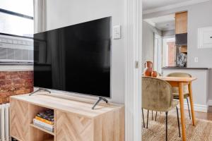 sala de estar con TV de pantalla plana en un centro de entretenimiento en Hip E Village 2BR w WD nr L Train NYC-824 en Nueva York