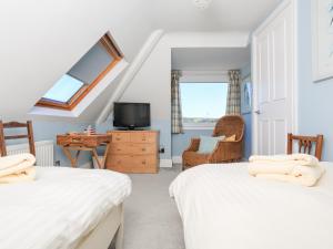 a bedroom with two beds and a tv and a chair at 2 Channel View in Salcombe +33 photos