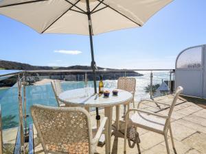 a table and chairs with an umbrella on a balcony at 2 Channel View in Salcombe