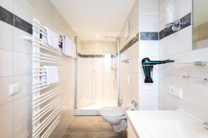 La salle de bains blanche est pourvue d'une douche et de toilettes. dans l'établissement Landhaus Vier Jahreszeiten, à Eriskirch