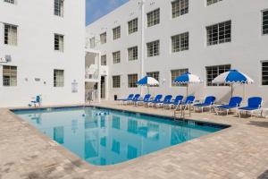 a pool in front of a building with blue chairs and umbrellas at Found Miami Beach powered by Sonder in Miami Beach