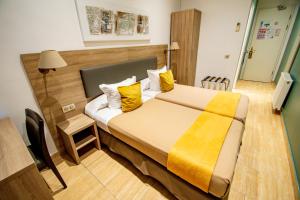 a hotel room with a large bed with yellow pillows at Hôtel Parisien in Nice