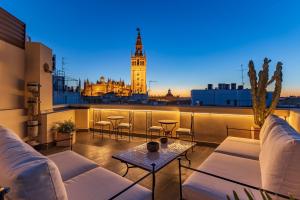 patio na dachu z kanapami i wieżą zegarową w obiekcie Angeles 6- Giralda Luxury by Valcambre w Sewilli