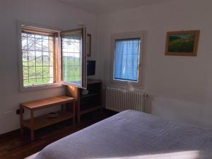 ein Schlafzimmer mit einem Bett und zwei Fenstern in der Unterkunft Casa di Campagna, Erbosa 2 