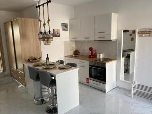a kitchen with white cabinets and a counter with a table at sofia guesthouse in Nea Skioni