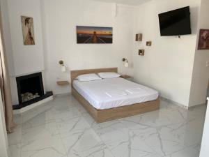 a white bedroom with a bed and a fireplace at sofia guesthouse in Nea Skioni