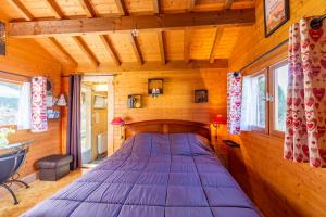 Cama grande en habitación con paredes de madera en Sauvage en Les Combes