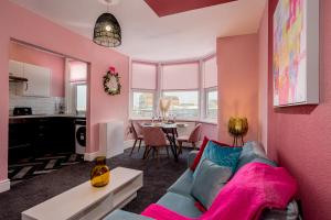 a living room with a blue couch and a pink wall at Charles Alexander Short Stay - Botanical House in Cleveleys