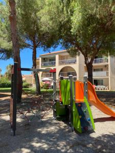 a playground in front of a building with trees at T2 RDC à Canet en Roussillon Europa 4 pers ,piscine,clim, tennis, parking in Canet-en-Roussillon
