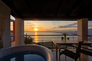 a balcony with a table and a view of the sunset at VergaView Luxury House in Kalamata