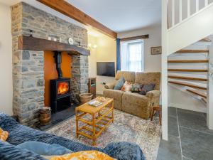 a living room with a stone fireplace and a couch at Ivy Bush Cottage in Llanddewi-Brefi