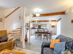 a living room with a staircase and a dining room and kitchen at Ivy Bush Cottage in Llanddewi-Brefi