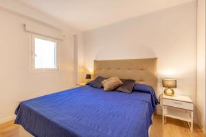 a bedroom with a blue bed and a window at Seafront Marina 1 Apartment in Pollença