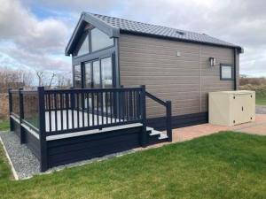 a tiny house with a porch and a yard at Chapel Fields Holiday Park in Chapel Saint Leonards