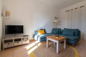 uma sala de estar com um sofá azul e uma televisão em BEL APPARTEMENT DANS LE CENTRE D'AVIGNON em Avignon
