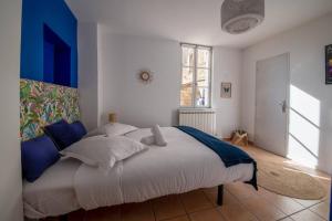 um quarto com uma grande cama branca com toques azuis em BEL APPARTEMENT DANS LE CENTRE D'AVIGNON em Avignon