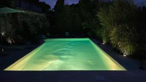 ein Schwimmbad in der Nacht mit einem beleuchteten in der Unterkunft LE PRIEURE DE BUFFON in Buffon