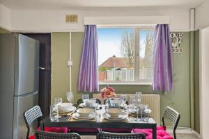 een eettafel met paarse gordijnen en een raam bij Large House with Parking and Garden - Sleeps 7 in Kent
