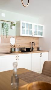 uma cozinha com armários brancos e uma mesa em Tarvil Apartmani - Zaovine em Bajina Bašta